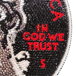 Macro shot of In God We Trust lettering in red crystals on a round dollar evening bag