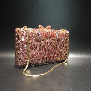 Detail of pink rhinestone evening clutch with crystal bow clasp and gold chain strap