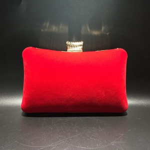 Detailed view of red velvet evening clutch featuring gold textured clasp and soft texture