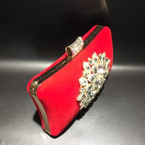 Detailed view of red velvet evening clutch with golden frame and radiant crystal flower