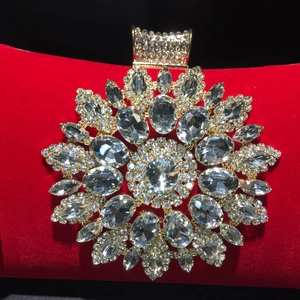 Detail of red velvet evening bag featuring crystal sunflower ornament and gold metal clasp