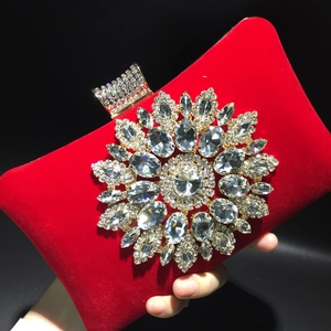 Detailed view of red velvet evening bag featuring a large sparkling crystal floral embellishment