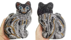 Détail d'une pochette chat sertie de strass brillants et d'yeux en cristal bleu