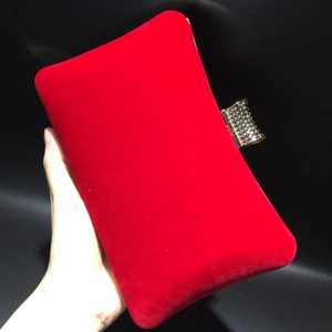 Detailed close-up of red velvet evening clutch with crystal-encrusted gold metal clasp