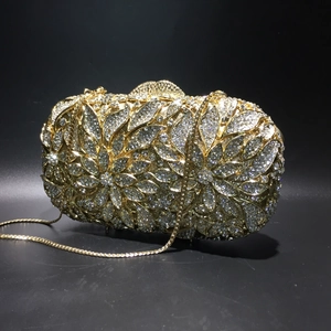 Detailed close-up of a luxury gold clutch bag with hollow metal flowers and crystals