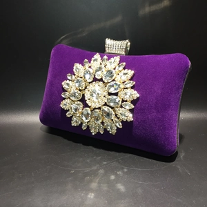 Detailed view of the purple velvet clutch bag with a large floral rhinestone decoration