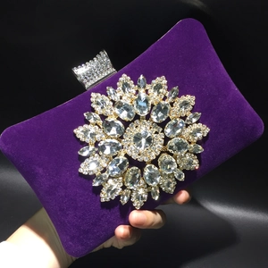 Detail of purple velvet evening clutch featuring a large rhinestone sunflower ornament