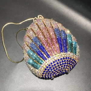 Macro shot of shell-shaped evening bag with colorful crystals and gold chain strap