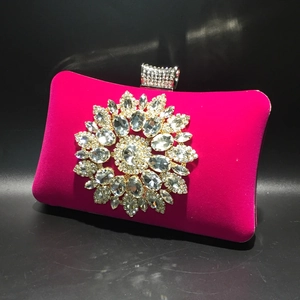 Close-up of fuchsia velvet evening bag with large sparkling rhinestone flower cluster