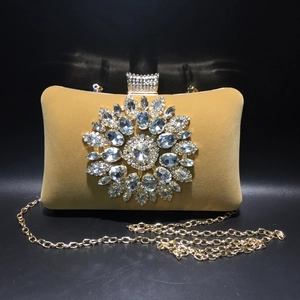 Close-up of yellow velvet evening bag with large rhinestone sunflower and gold chain