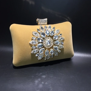 Macro detail of sunflower crystal ornament on yellow velvet evening clutch bag