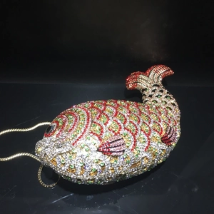 Macro shot of fish-shaped evening bag with colorful crystals and gold chain strap