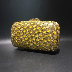 Detailed close-up of golden evening clutch bag featuring yellow marquise crystal embellishments