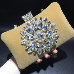 Macro detail of velvet evening bag featuring sparkling rhinestone sunflower and gold chain