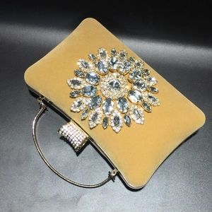 Detail of crystal sunflower buckle on luxury golden velvet evening clutch bag