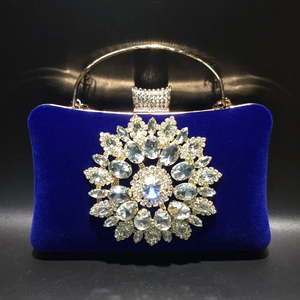 Detail of royal blue velvet evening bag with large sunflower rhinestone ornament and gold handle