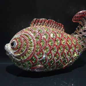 Luxury fish shaped evening clutch bag encrusted with colorful crystals on black background