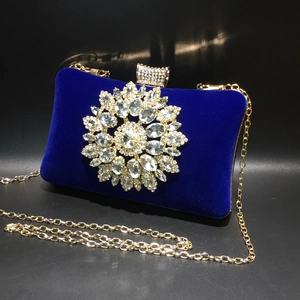Detail of royal blue velvet clutch bag with sunflower rhinestone brooch and gold chain