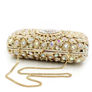 Close-up of golden evening clutch bag with iridescent rhinestones and white pearls