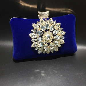Close-up of royal blue velvet evening bag with ornate crystal flower embellishment