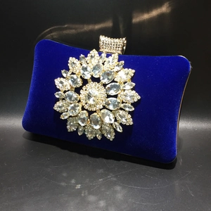 Macro view of royal blue velvet evening bag with crystal sunflower ornament