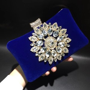 Royal blue velvet evening clutch with a sparkling rhinestone flower held by a hand