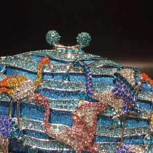 Détail de pochette de soirée avec paillettes bleues et motif de flamant rose en cristaux