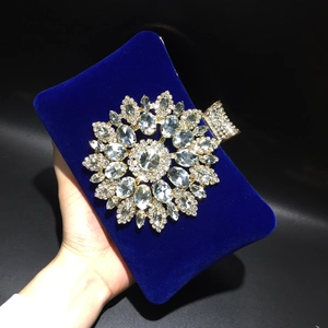 Macro detail of royal blue velvet clutch featuring a sparkling crystal sunburst ornament