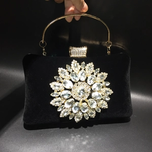 Close-up of black velvet evening bag with large crystal flower and gold ring handle