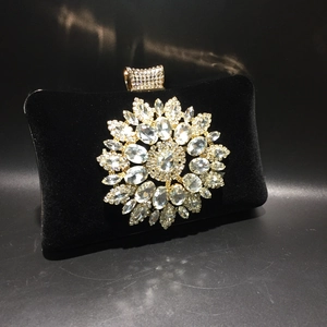 Detail of a black velvet evening bag with a large sparkling rhinestone flower ornament