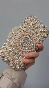 Macro detail of gold evening clutch featuring sparkling crystals and pearl embellishments