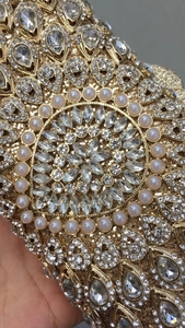 Close-up of luxury gold evening bag featuring radial teardrop rhinestones and pearls