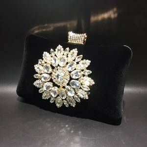 Macro detail of the sparkling sunflower rhinestone ornament on the black velvet clutch bag