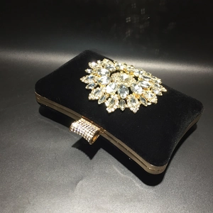 Close-up of black velvet evening bag with crystal sunflower ornament and rhinestone clasp