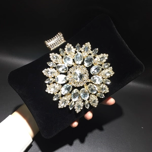 Detail of luxury black velvet evening clutch featuring a large sunflower rhinestone ornament