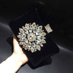 Close-up of black velvet evening bag featuring a large sparkling rhinestone flower ornament