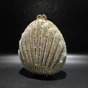 Macro shot of shell-shaped evening bag with dense white rhinestones and gold hardware