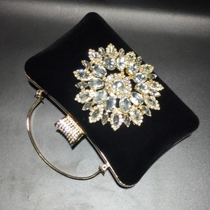 Detail of black velvet evening bag with large rhinestone flower and gold ring handle