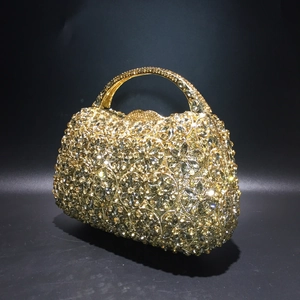 Detailansicht der goldenen Abendtasche mit floralem Strassmuster und gewölbtem Metallgriff