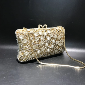 Close-up of gold metal evening clutch with white cat-eye stones and crystal heart clasp