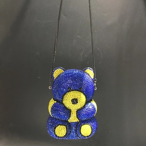 Detail of teddy bear clutch bag fully encrusted with blue and yellow sparkling rhinestones