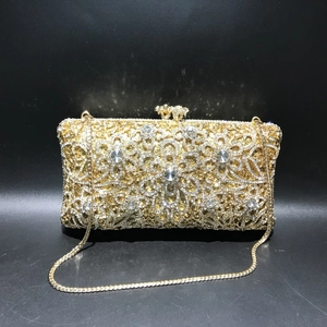 Close-up of golden hollow flower pattern with rhinestones on luxury evening clutch bag