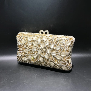 Close-up of golden evening clutch featuring crystal pavé, cat-eye stones and heart clasp