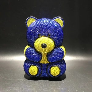 Detail shot of the bear-shaped evening clutch featuring vibrant blue and yellow rhinestones