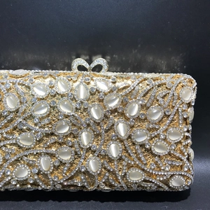 Luxury gold evening clutch bag with white cat-eye stones and crystal bow clasp