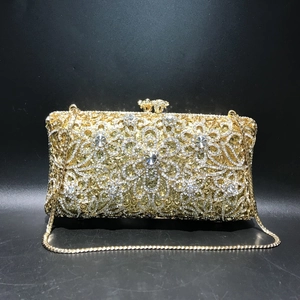 Detail of luxury gold evening bag featuring hollow floral pattern and crystal rhinestones