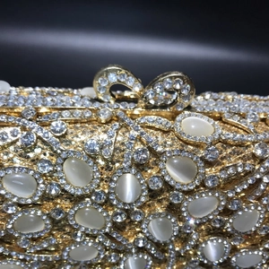 Detail of luxury gold evening clutch featuring inlaid rhinestones and cat-eye stones