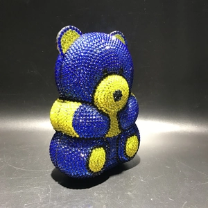 Macro shot of blue and yellow crystal-encrusted bear evening bag on black background