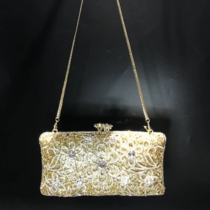 Close-up of golden hollow metal evening bag with intricate floral rhinestone patterns