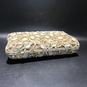 Detailed close-up of a gold luxury evening clutch bag with cat-eye stones and rhinestones